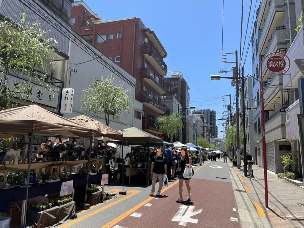 植木の露店が並ぶ通り。緑のテントの下に様々な植物が並ぶ。