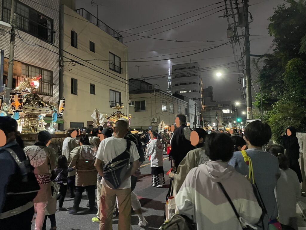 夜の沿道に集う、お祭りの人々。