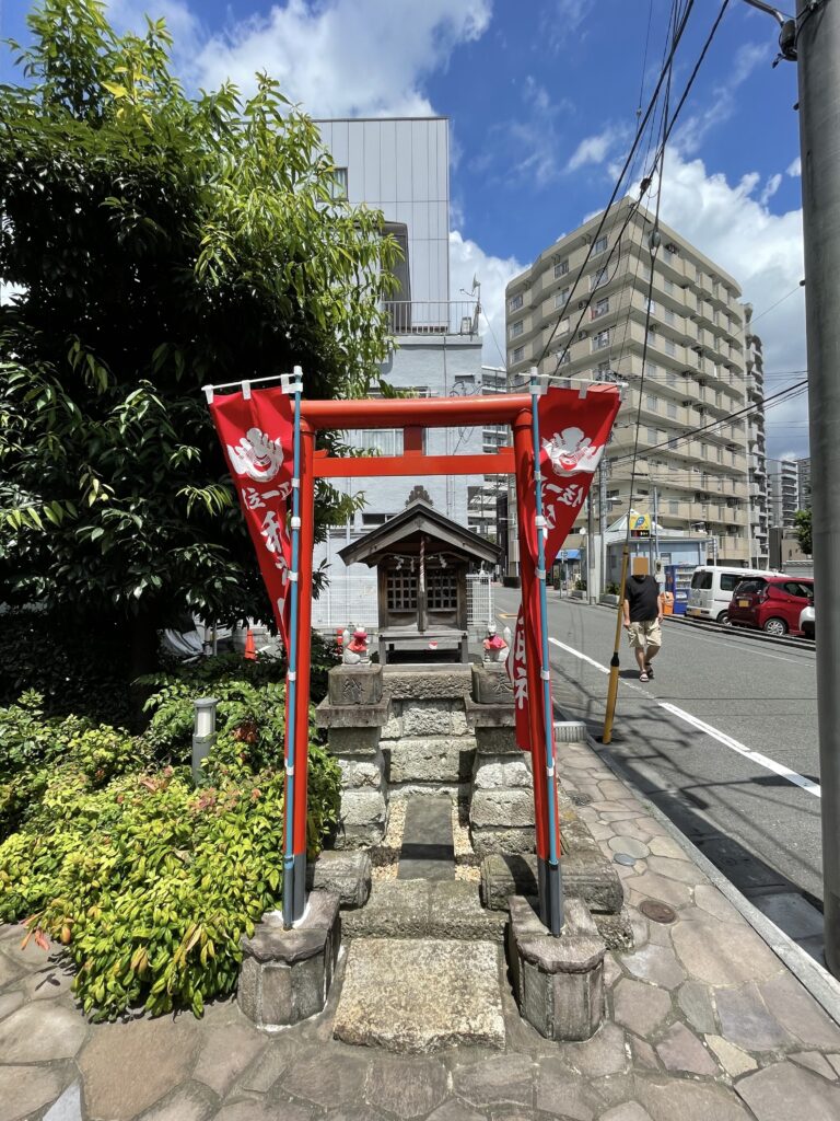 朱色の鳥居に、赤い幟が揺れる。町かどの、小さなお社。