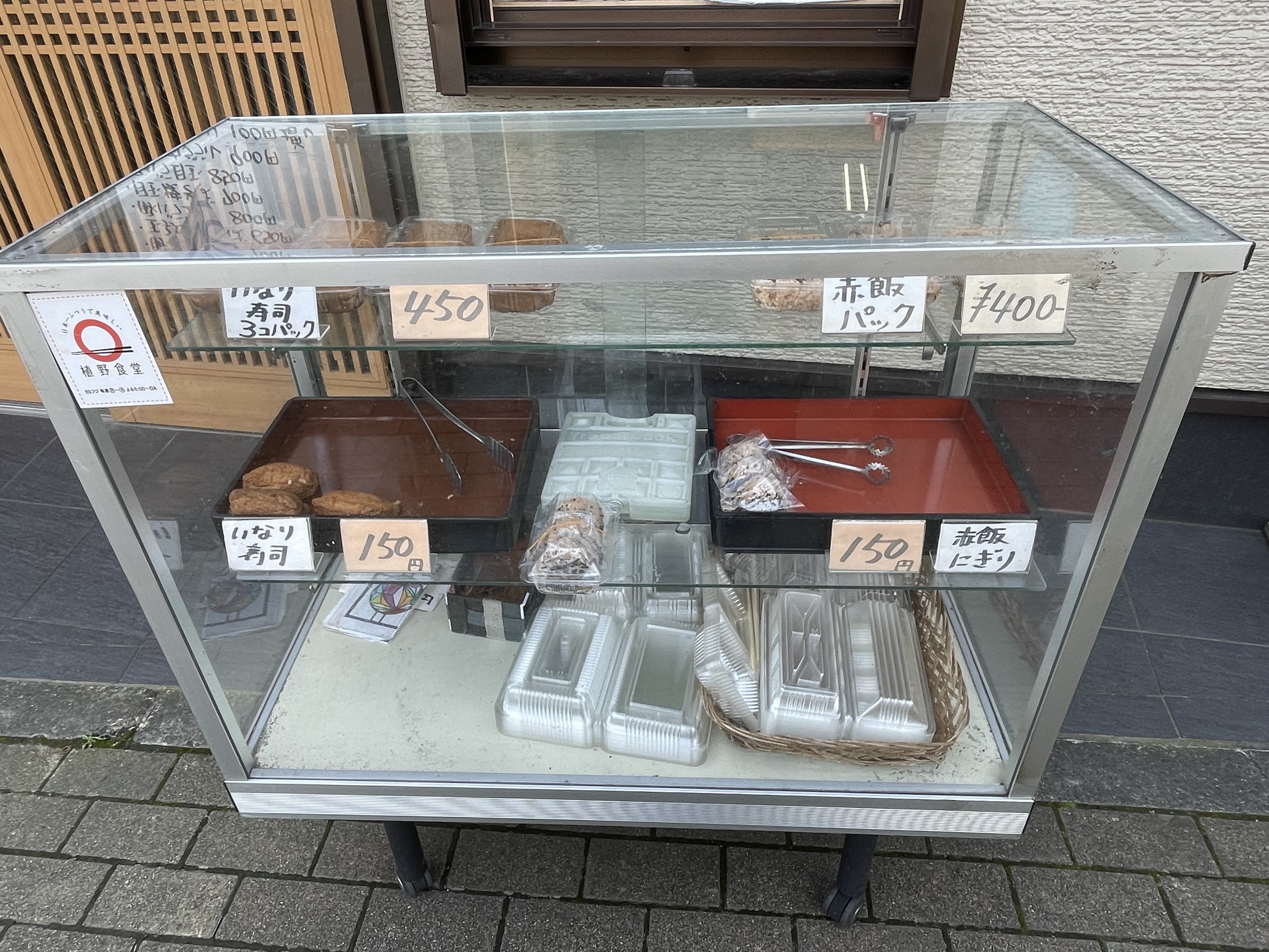 入口前にあるショーケースには「赤飯パック」「赤飯おにぎり」「いなり寿司」があります