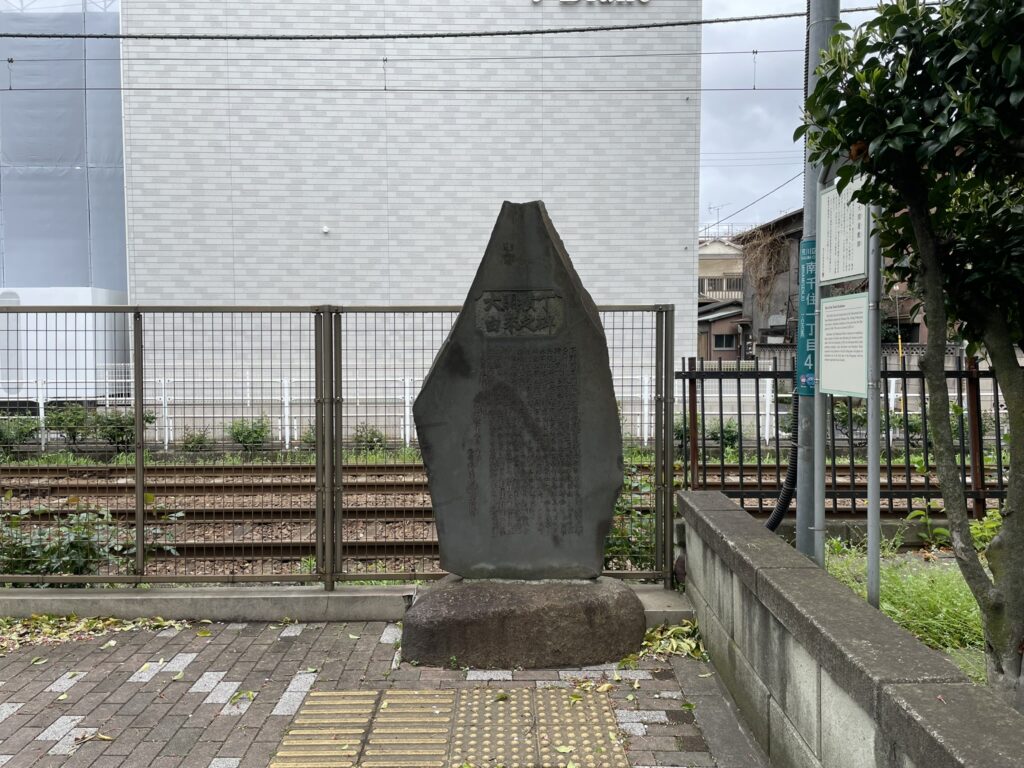 大関横丁由来之碑と刻まれた石碑。都電荒川線の線路沿い、荒川区南千住側に立つ(2026年4月撮影)