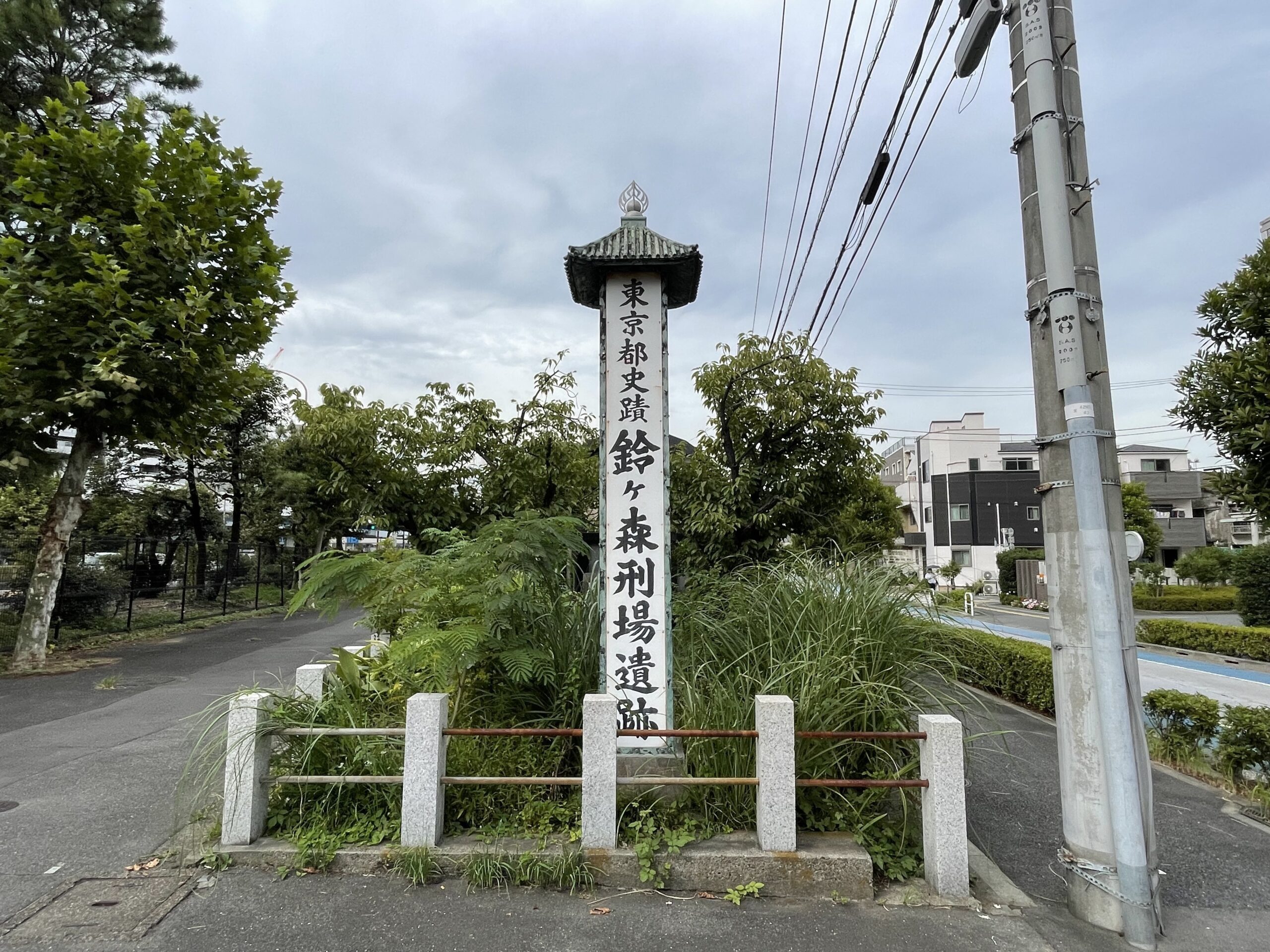 頂に宝珠をのせた屋根付きの標柱。周りの草木に埋もれるように立っている