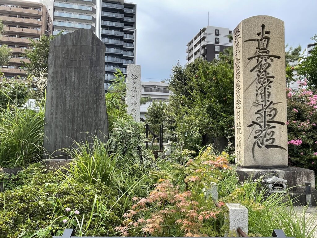 右の題目塔の側面には「衆罪如霜露 慧日能消除」の経文が刻まれている。中央奥にある石柱は「鈴ヶ森刑場受刑者之墓」