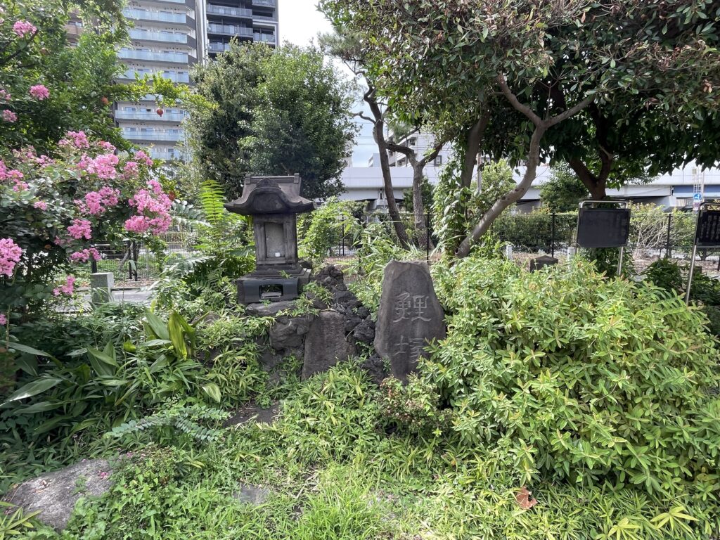 「鯉塚」と刻まれた石碑と、屋根付きの石の祠が並ぶ