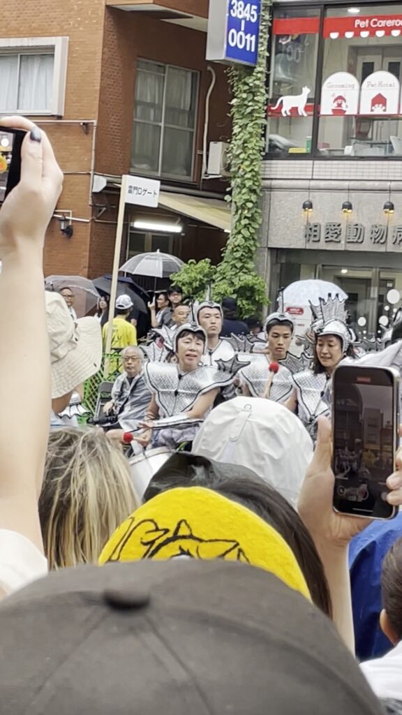 銀色の衣装で太鼓を叩きながら進むチーム。