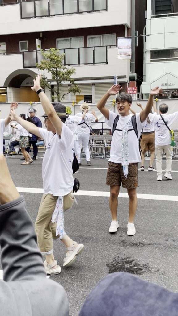 白いTシャツ姿で、手を挙げて踊る参加者の方々。
