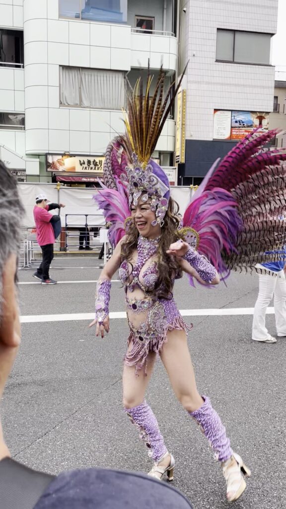 紫の羽根とビーズの衣装で踊るダンサー。